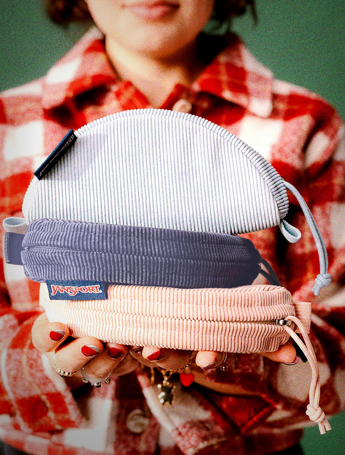Person holding three striped jansport pouches with a plaid shirt in the background