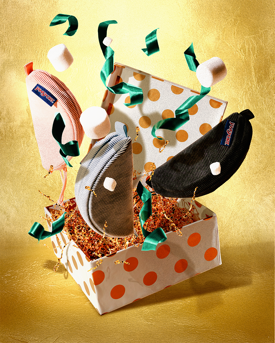 Three Jansport Pouches in a box with polka dot pattern on a gold background