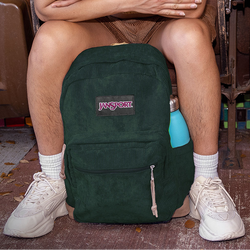 Person sitting on a bench with a green Jansport backpack and a blue water bottle.